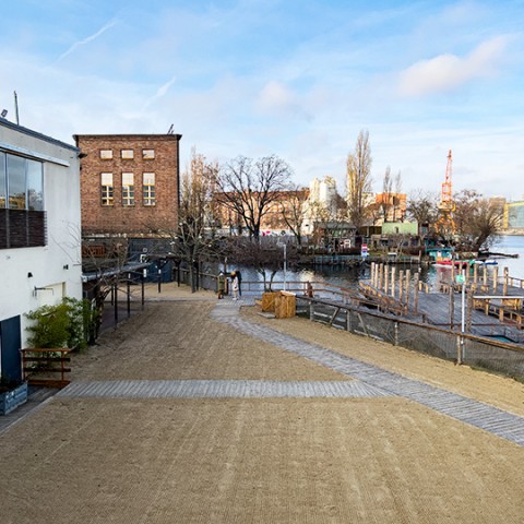 Blick von oben auf Außengelände mit Strand vor Badeschiff