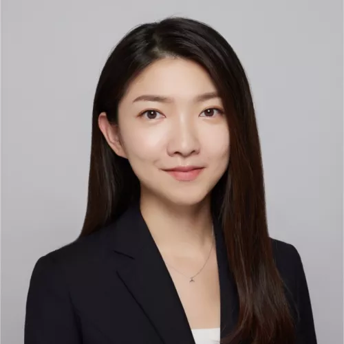 Portrait photo of a woman wearing a dark blazer, facing the camera with a neutral background.
