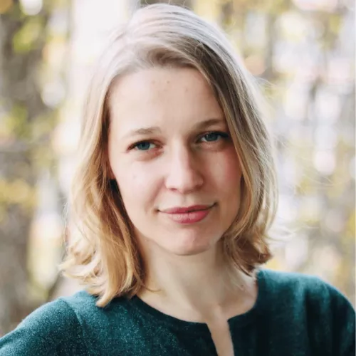 Auf dem Bild ist Julia Bauer im Profil zu sehen. Sie trägt ein grünes Oberteil. Im Hintergrund sind Bäume zu erkennen.