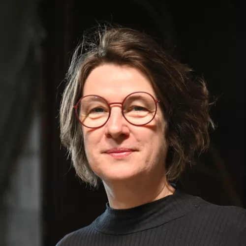 Jo Tiffe vor dunklem Hintergrund lächelnd in die Kamera blickend