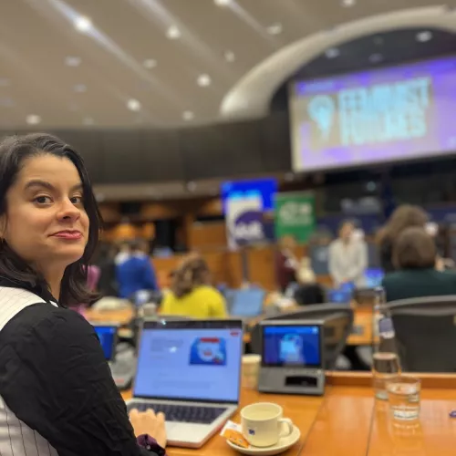 Woman at the parliament looking at the camera with a screen in the back