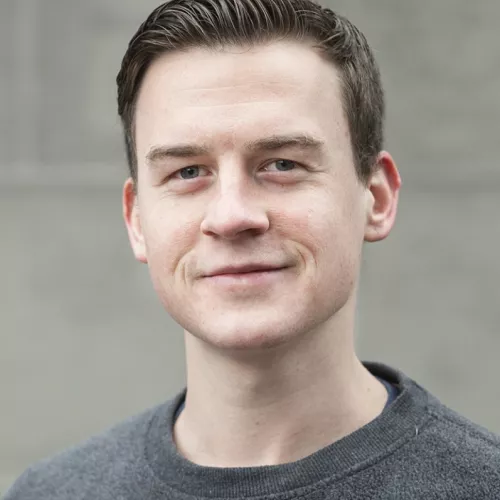 Junger Mann mit kurzen braunen Haaren auf die Seite gegelt.