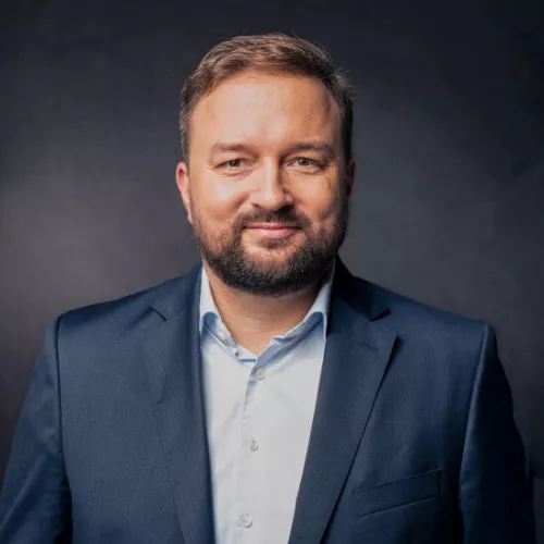 Porträt von Michael Hose im blauen Anzug mit Hemd und Krawatte vor neutralem Hintergrund.