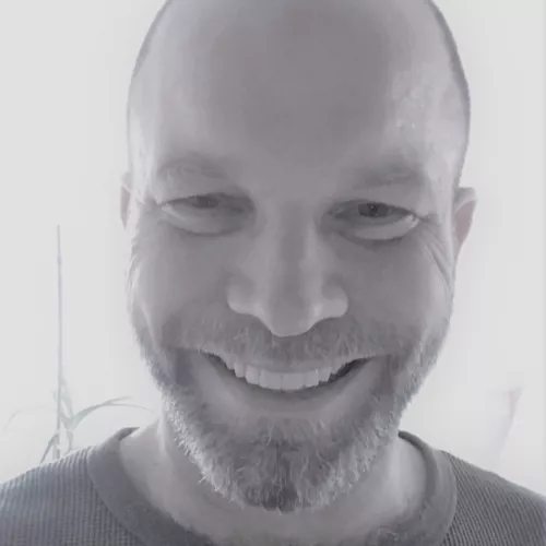 Kurzhaariger Mittvierziger mit freundlichem, optimistischem Lächeln im Gesicht. 