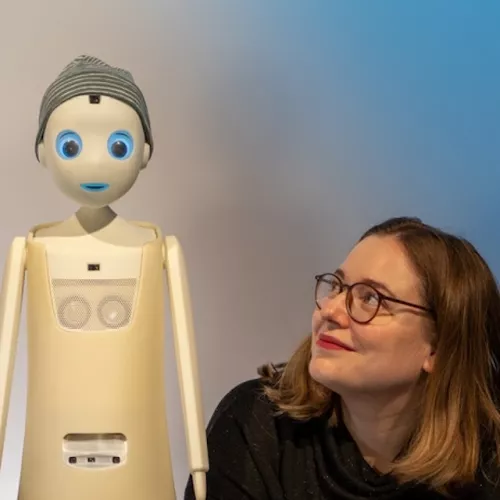 links ein roboter, rechts katharina weitz die ihn ansieht und lächelt