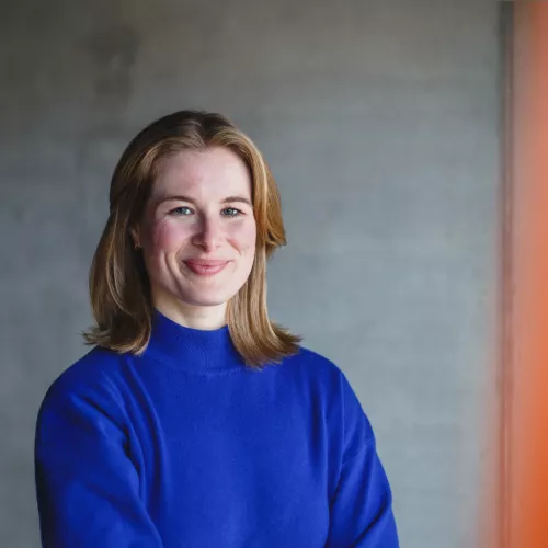Blonde Frau, blauer Pullover, grauer Hintergrund