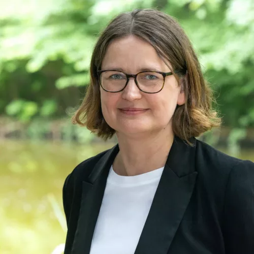 Porträt Tanja Maier vor grünem Hintergrund mit Wald
