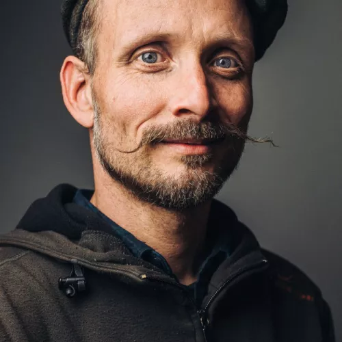 Mann mit Kappe, Bart trägt Hoodie
