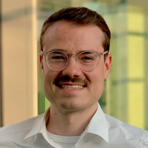 Picture of a man with glasses and mustache in white collar shirt.