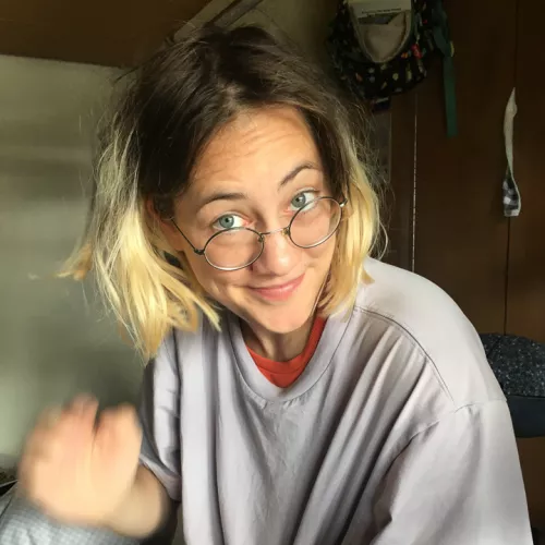Amelie sitzt im Nachtzug und schaut lustig über ihre Brillengläser