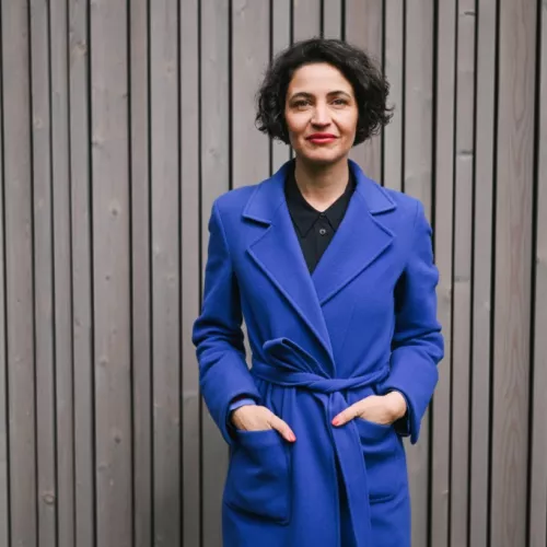 Anna-Lena in blauem Mantel vor heller Wand