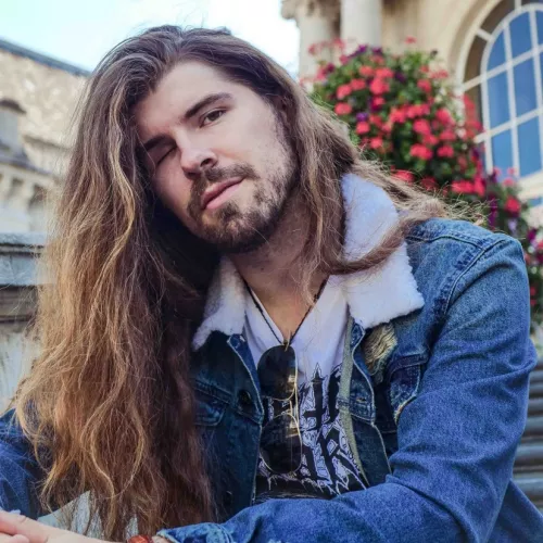 Alexander Prinz sitzt lässig vor einem Blumenbouquet in Spa und tut so als wäre er ein Instagram Modell 