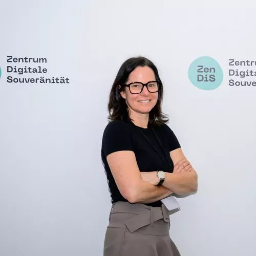 Foto von Pamela Krosta-Hartl vor Logo-Wand mit ZenDiS-Logos.