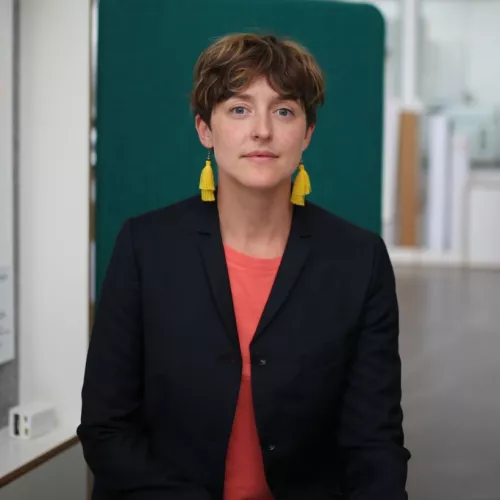 Person mit kurze Haare und gelbe Ohrringe