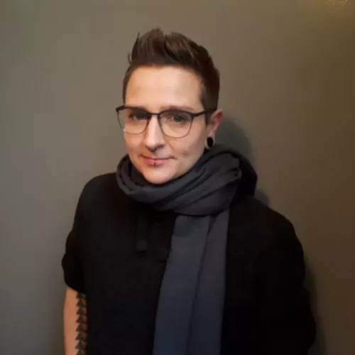 Abgebildet ist Steff Urgast, eine Person mit kurzen dunklen Haaren, einer Brille und dunkler Kleidung.